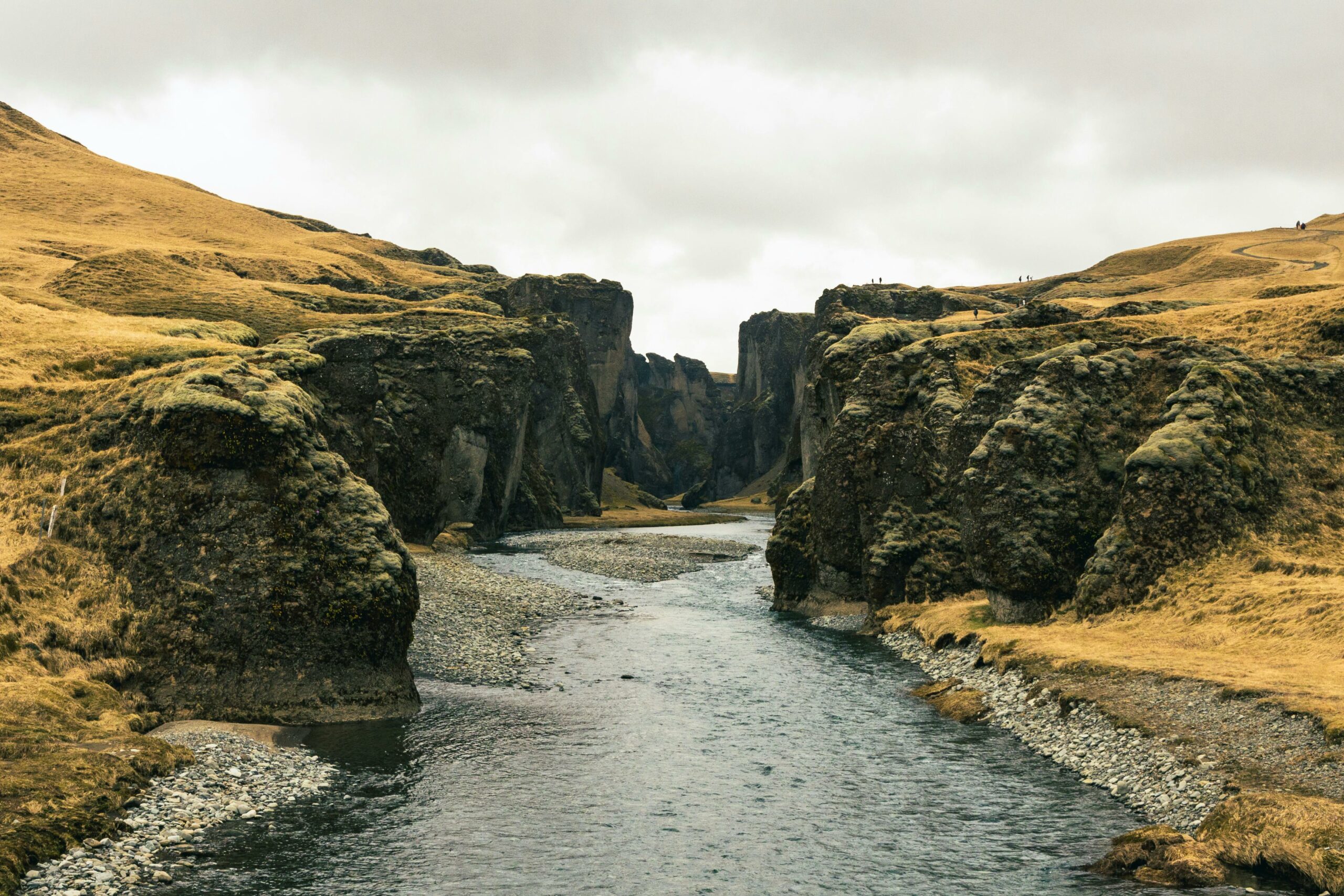 Breathtaking view of a river flowing through a rocky gorge under a cloudy sky.