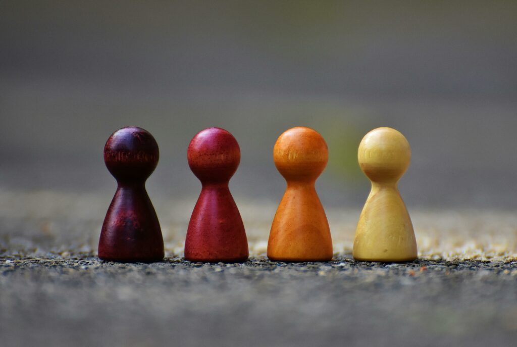 Close-up of four colorful wooden pawn pieces arranged in a row.